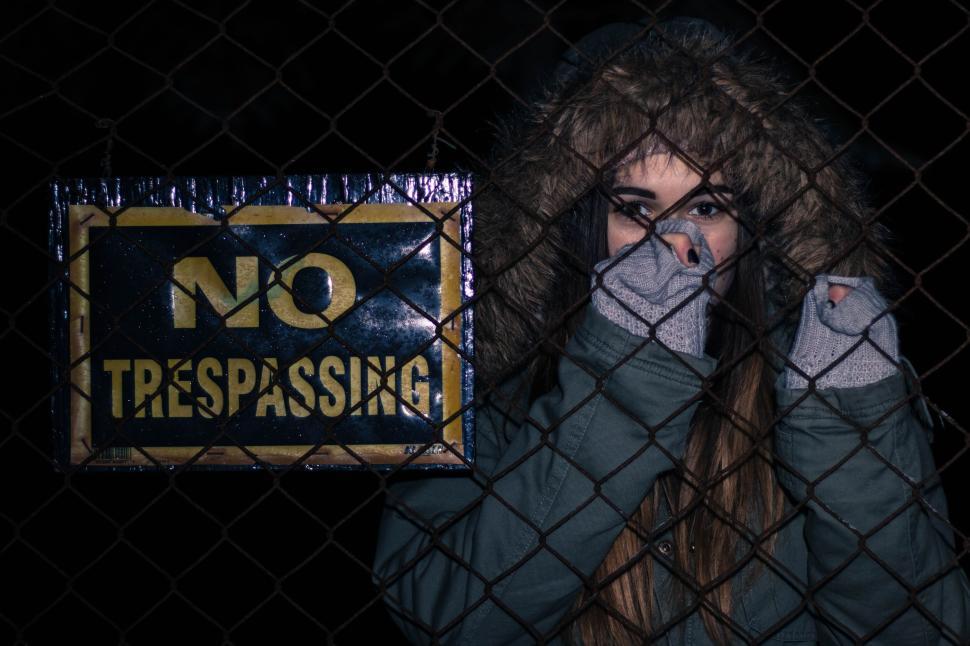 Free Image of Person behind wire fence near a  No Trespassing  sign. 