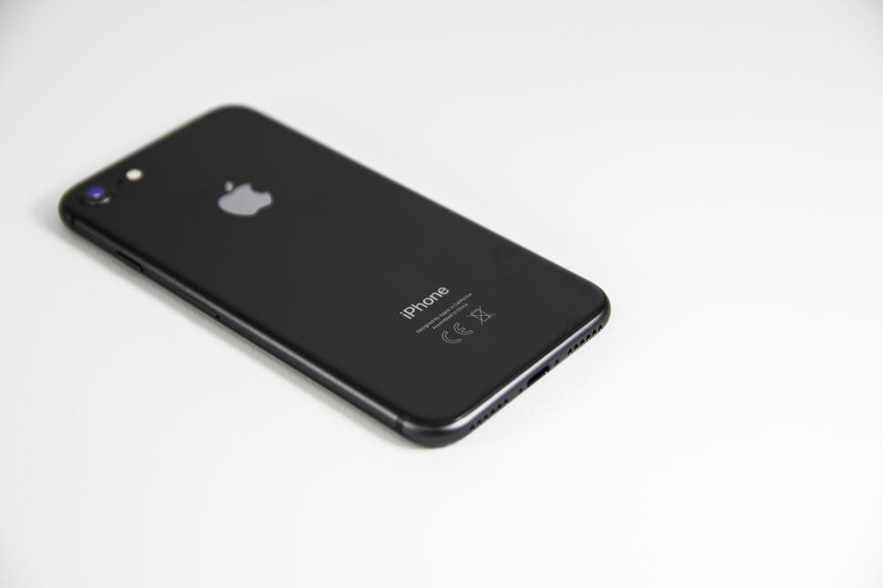 Free Image of Modern black iPhone placed on a white background surface. 