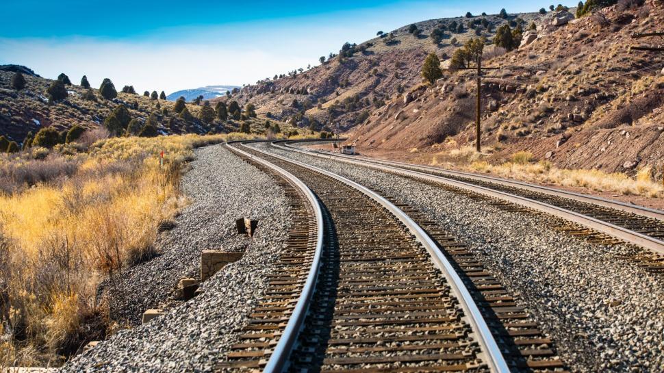 Free Image of Curving railroad tracks through dry hills and clear sky 