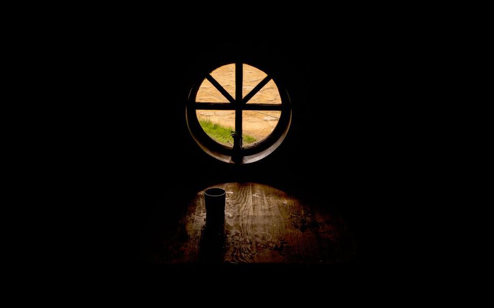 Free Image of Circular window view casting light on rustic wooden table 