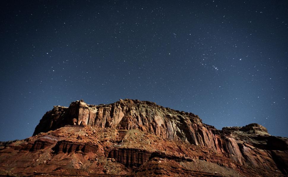 Free Image of Starry night sky with rocky mountain silhouette below 