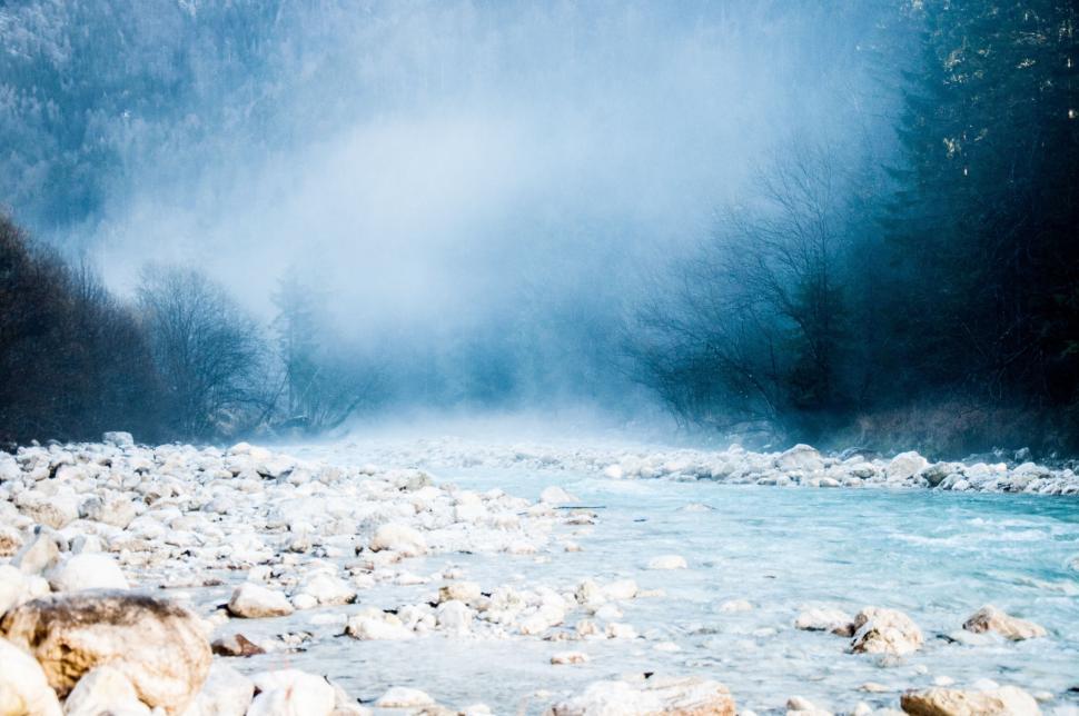 Free Image of Mist rising over rocky riverbed in winter forest scene 