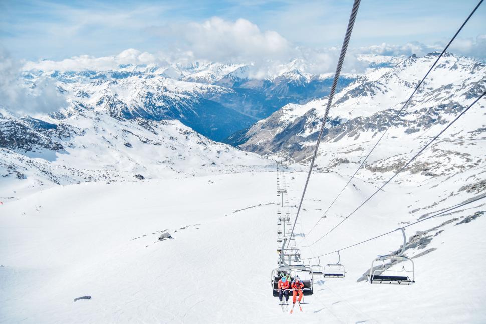 Free Image of Ski lift ascending snowy mountain under clear skies 