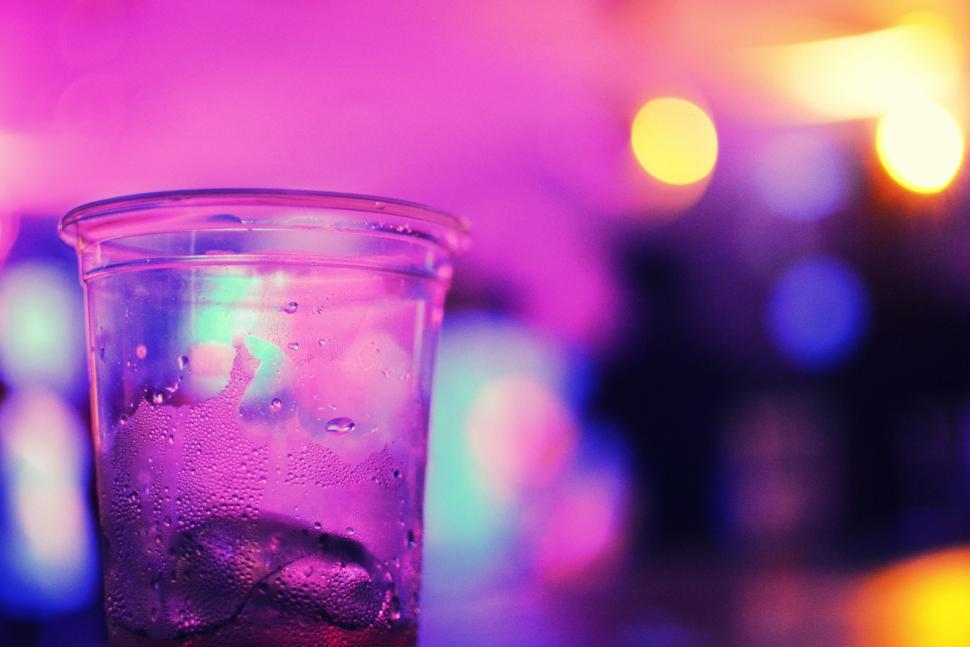 Free Image of Vibrant plastic cup with condensation, intense neon bokeh 