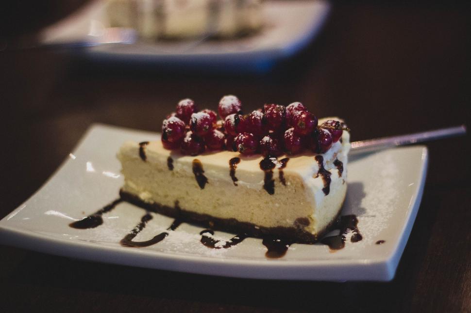 Free Image of Cheesecake slice with red berries and chocolate drizzle 
