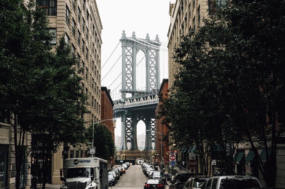 Free Image of Brooklyn Bridge framed by Manhattan street with parked cars 