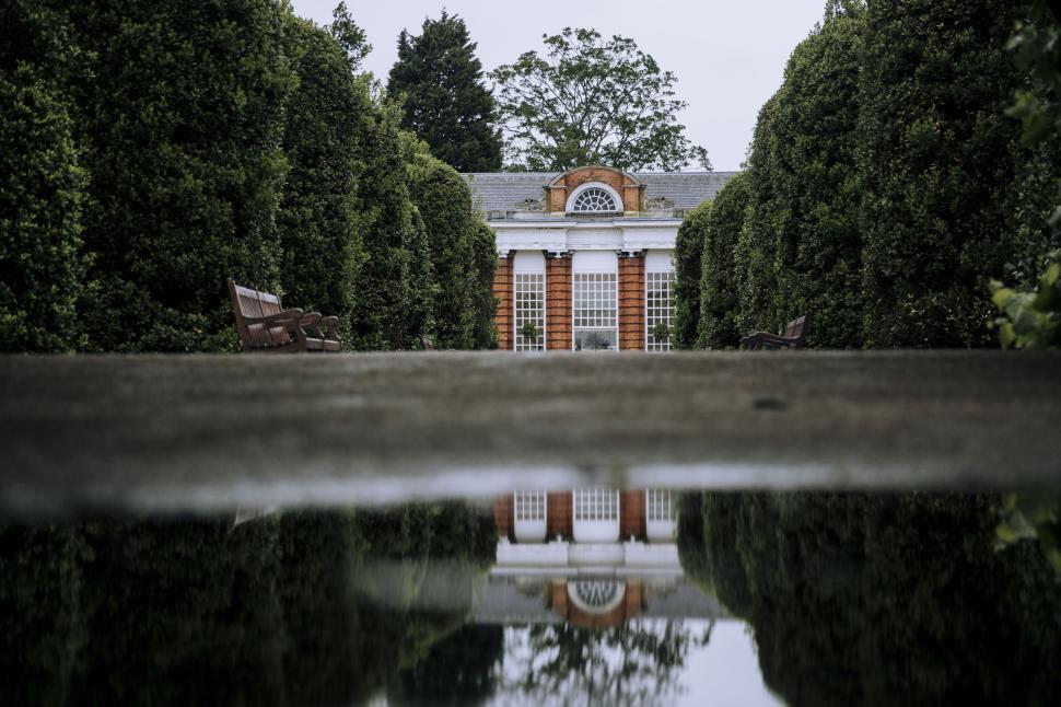 Free Image of Symmetrical reflection of a building with lush hedges 