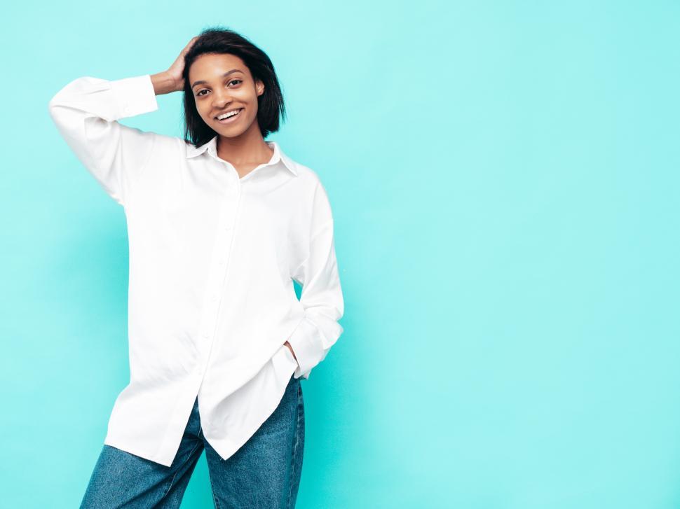 Free Image of Woman posing smiling, white shirt, turquoise background 