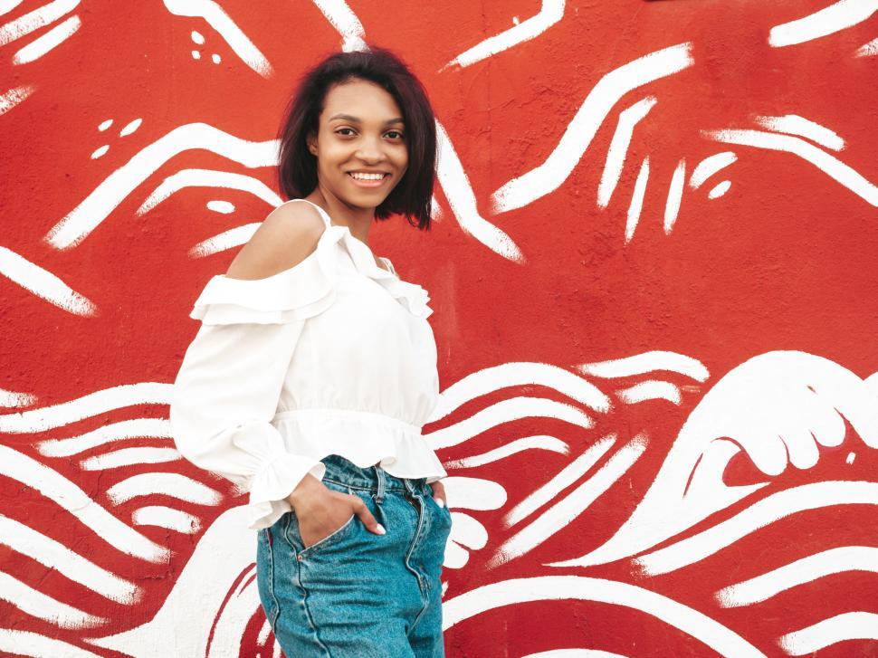 Free Image of Woman stylish pose, red wall, trendy fashion, casual jeans 
