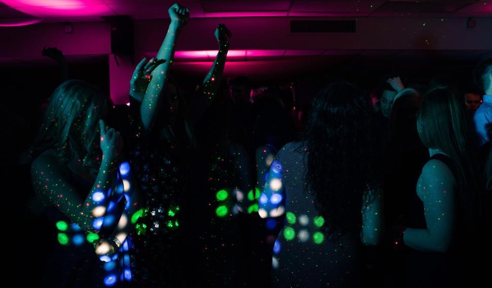 Free Image of Crowd dancing under pink and green lights at party. 