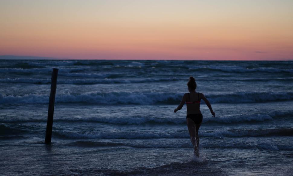 Free Image of Person running towards the ocean during twilight hours. 