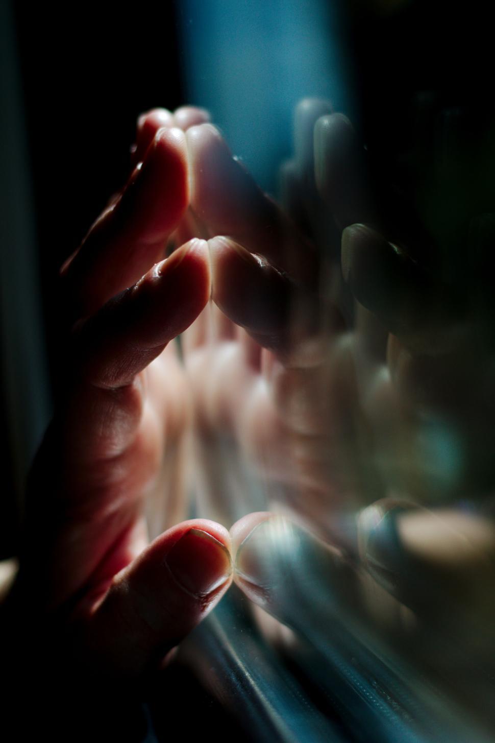 Free Image of A hand touching a reflective surface with light play 