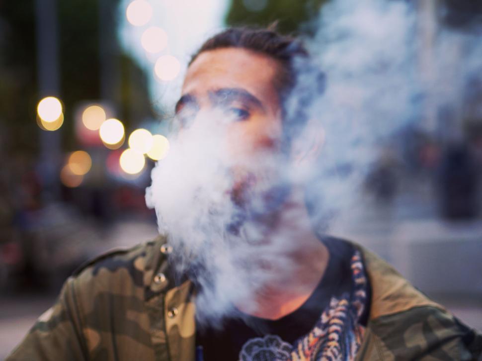 Free Image of Person exhaling vapor in an outdoors setting at dusk. 