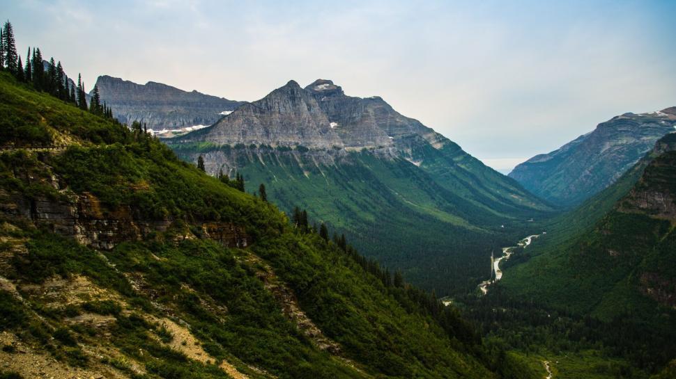 Free Image of Vast green valley with towering rocky mountains all around 