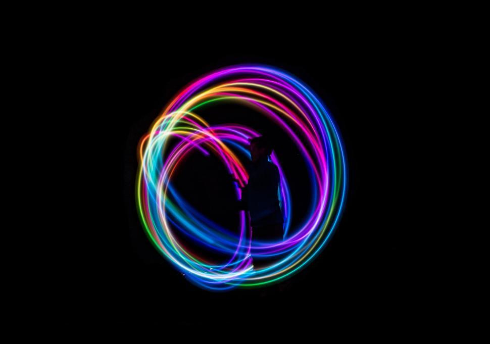 Free Image of Vibrant neon light trails forming artistic circular patterns. 