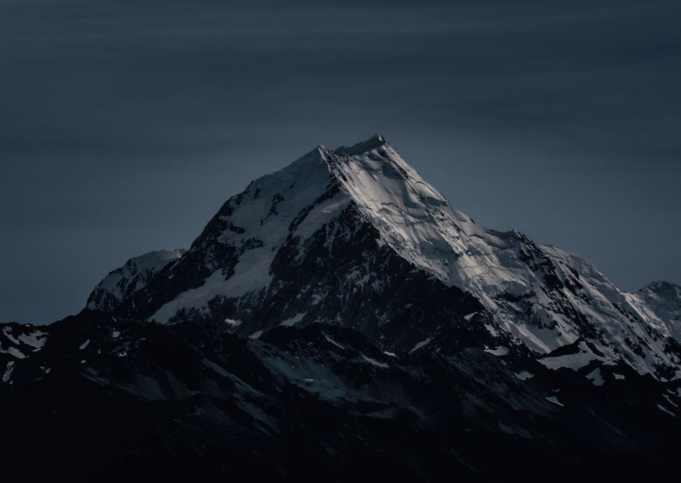 Free Image of Snow-covered mountain peak towering under dark skies 