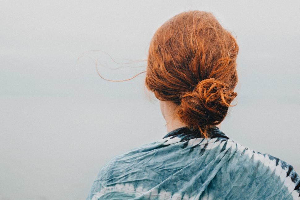 Free Image of A person with red hair facing away, near water body. 