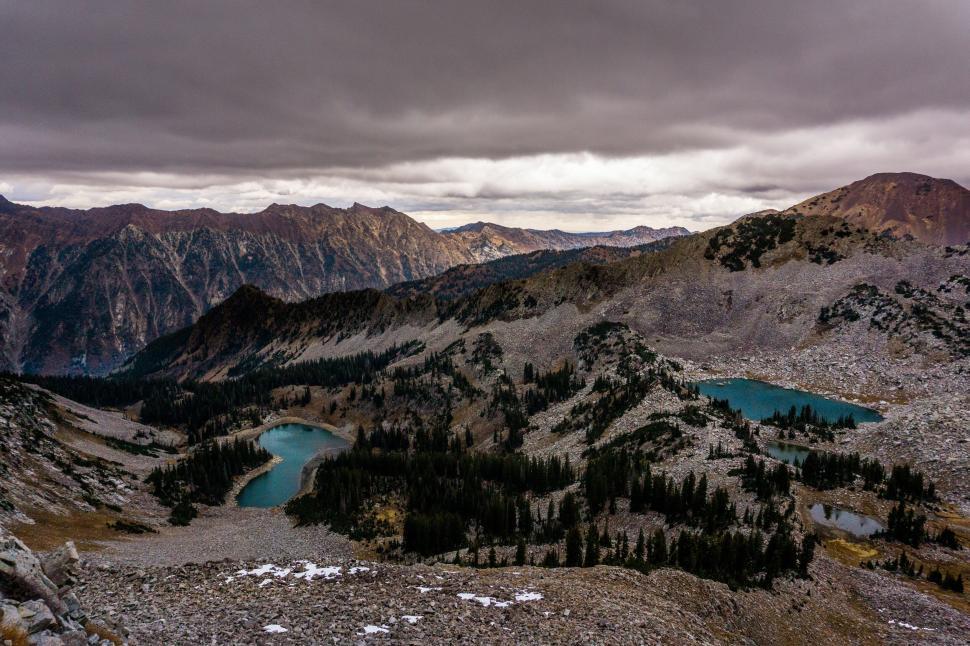 Free Image of Mountains and lakes under a cloudy sky in the distance. 