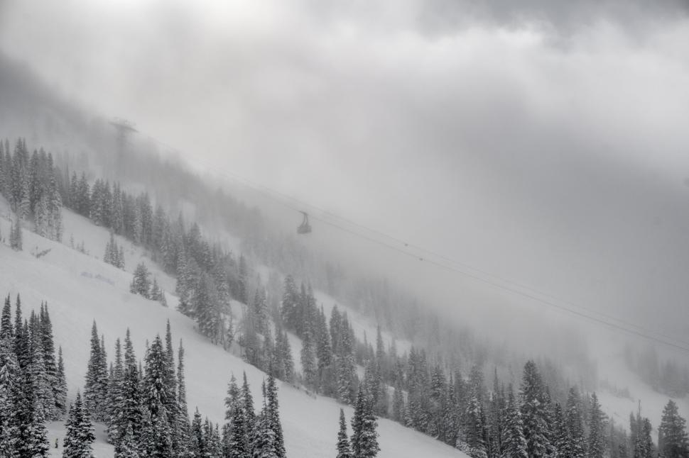 Free Image of Cable cars move through snowy mountain under heavy mist 