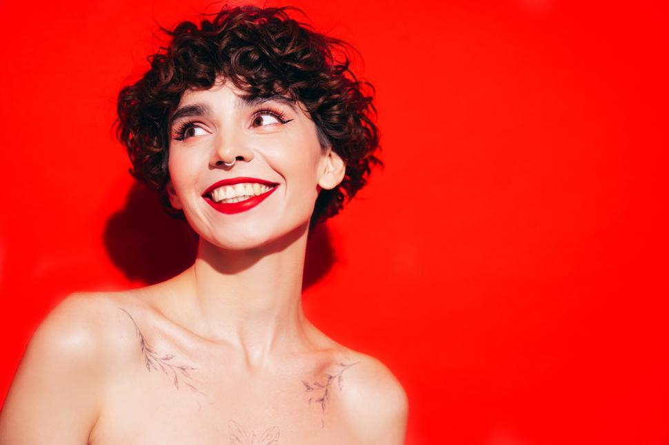 Free Image of Smiling woman with short curly hair against red background. 