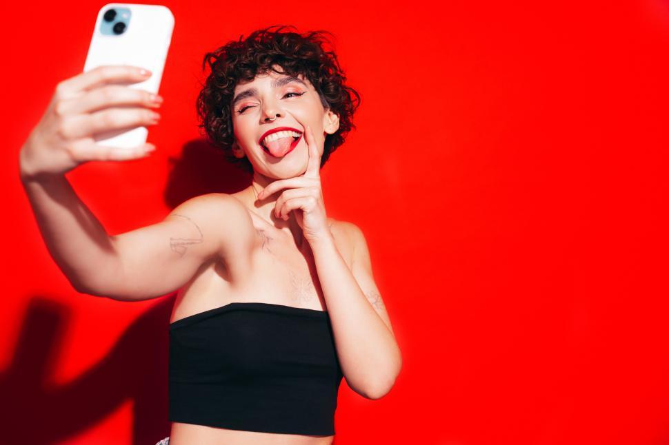 Free Image of Woman taking selfie with phone, pulling a funny face. 