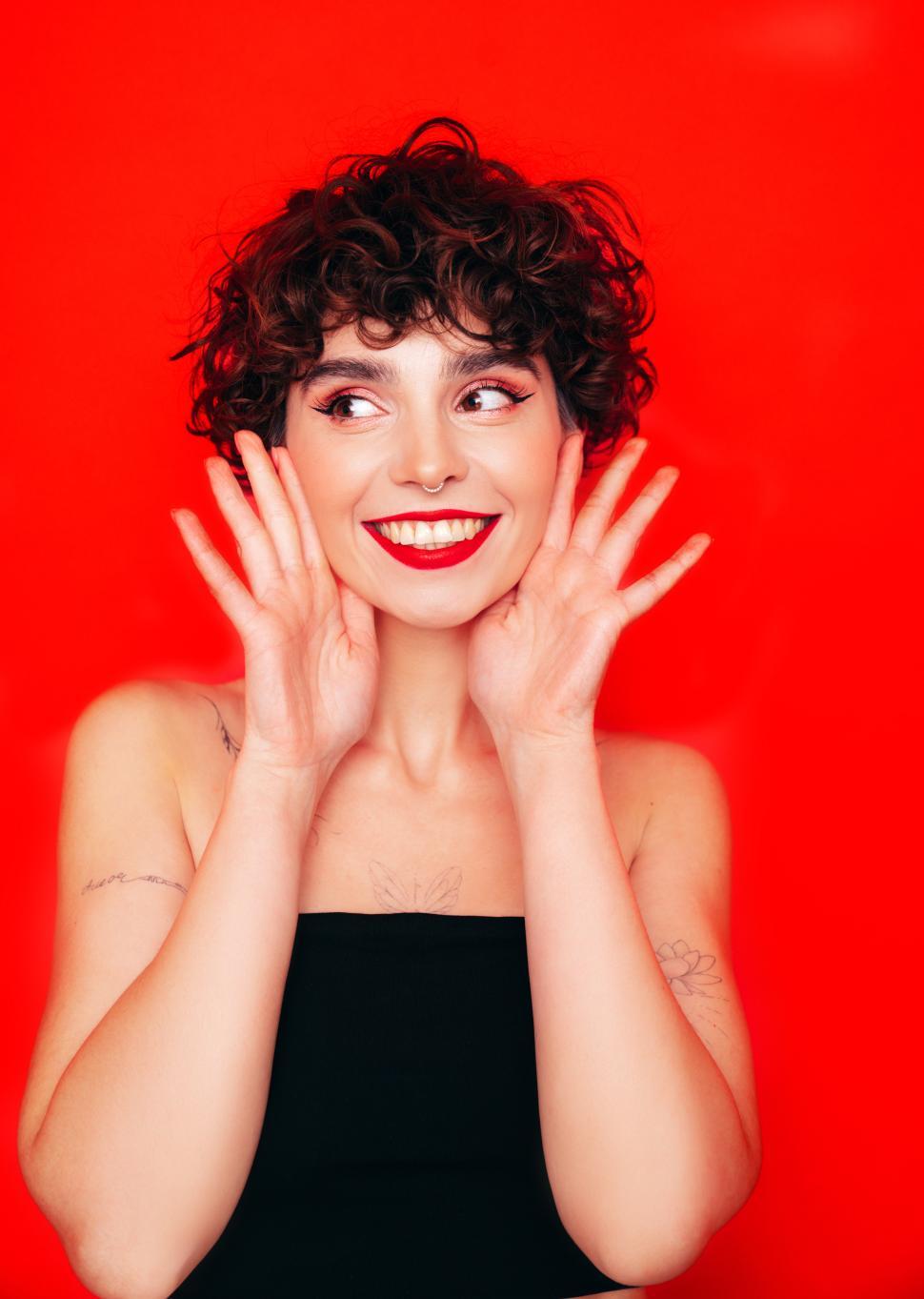 Free Image of Surprised woman with hands near face, red background. 