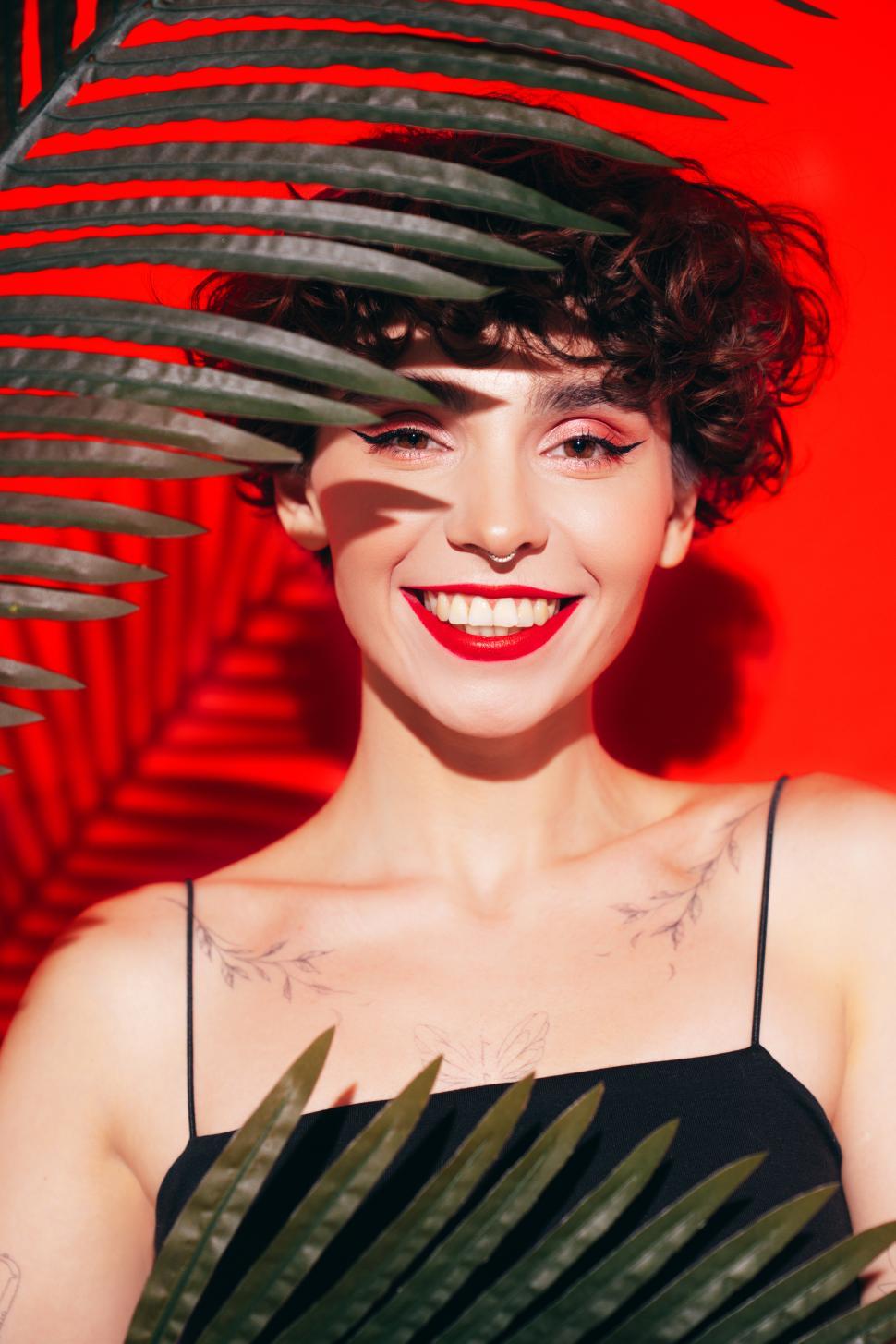 Free Image of Smiling woman with short hair in front of red backdrop 