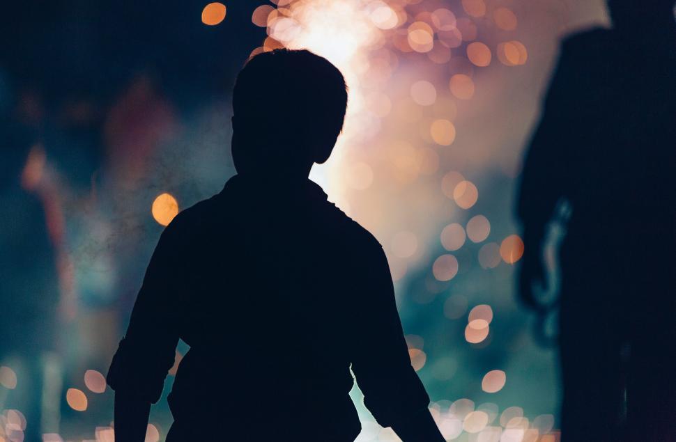 Free Image of Silhouette of child with vibrant bokeh lights background. 