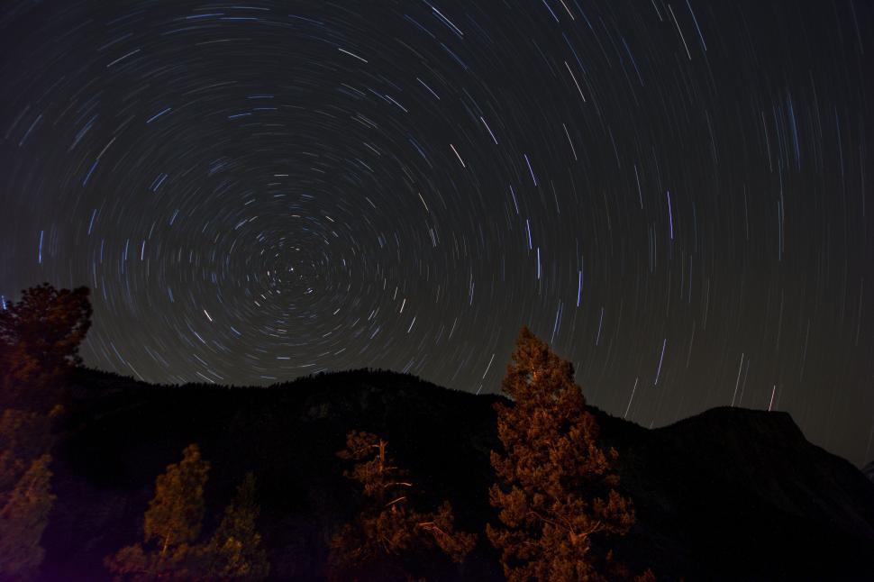 Free Image of Star trails over mountain landscape at night time 