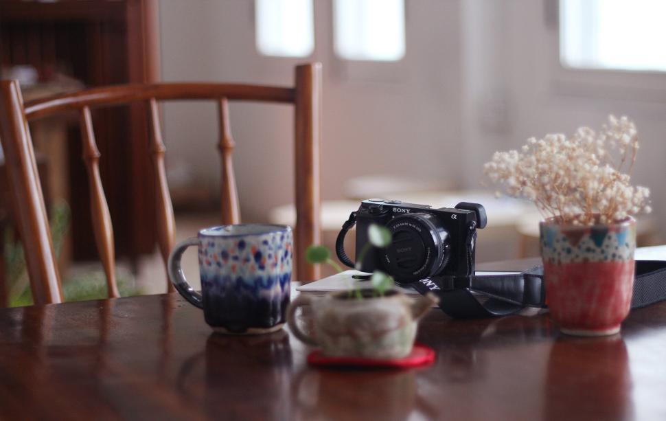 Free Image of Cozy indoor setup with mugs and camera on wooden table 