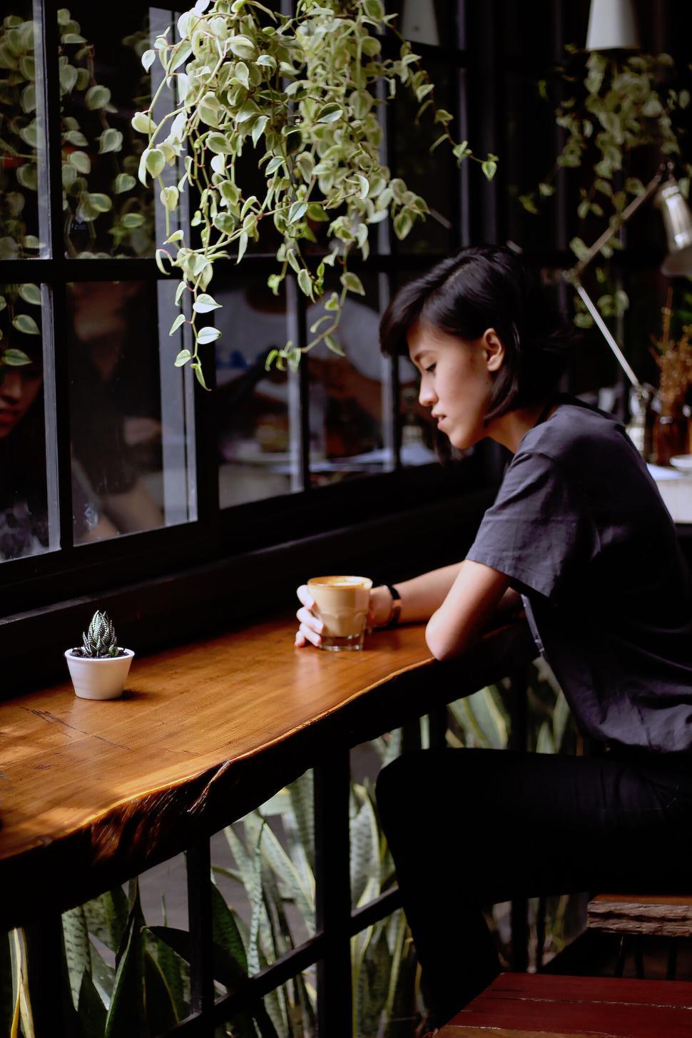 Free Image of Woman enjoying a cup of coffee in a cozy cafe 
