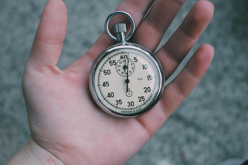 Free Image of Hand holding a vintage stopwatch on a textured surface 