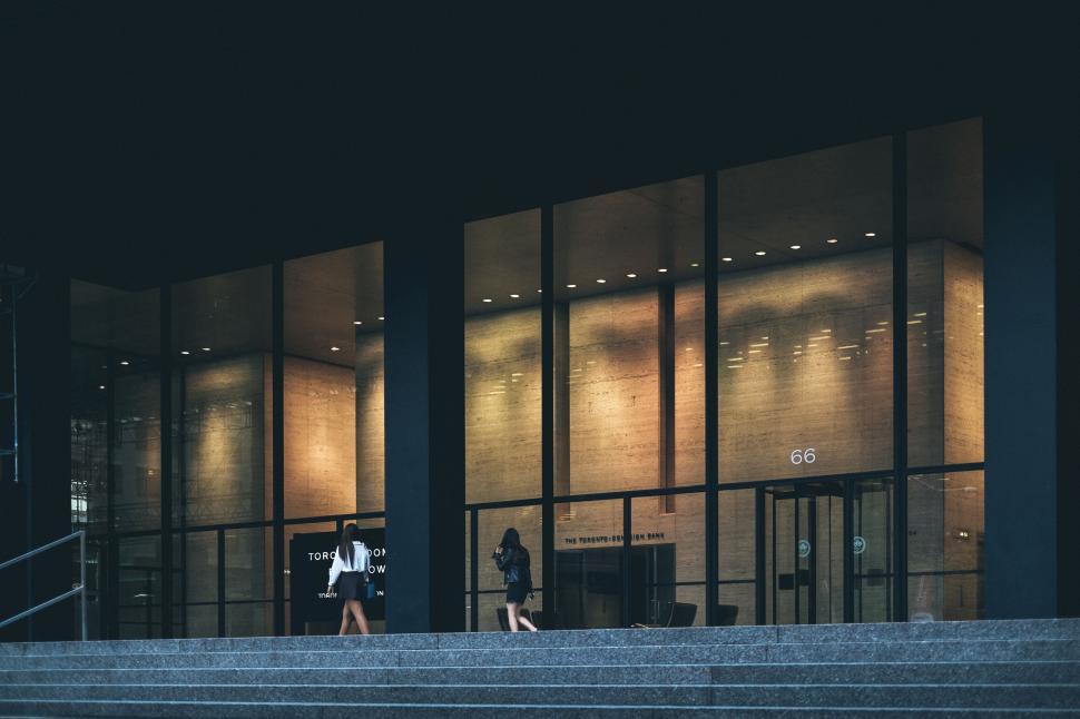 Free Image of Two women walking near illuminated building entrance at night. 