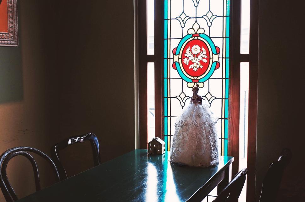 Free Image of Stained glass window with ornate wooden table inside 