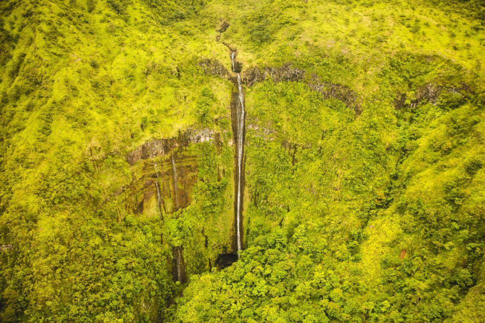 Free Image of Waterfall cascading down lush green mountainside landscape. 