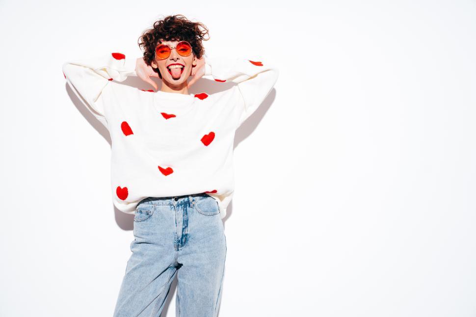 Free Image of Playful woman in heart sweater sticking out tongue, white background 