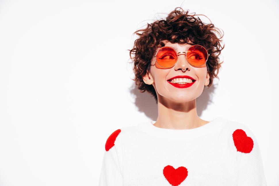 Free Image of Smiling woman with short hair in heart sweater, white background 