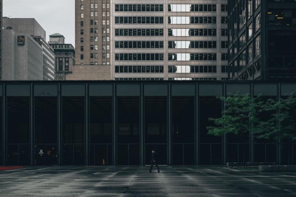 Free Image of Man walking in the rain near high-rise buildings. 