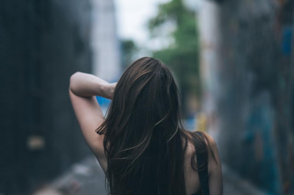 Free Image of Woman with long hair walking through narrow alleyway. 