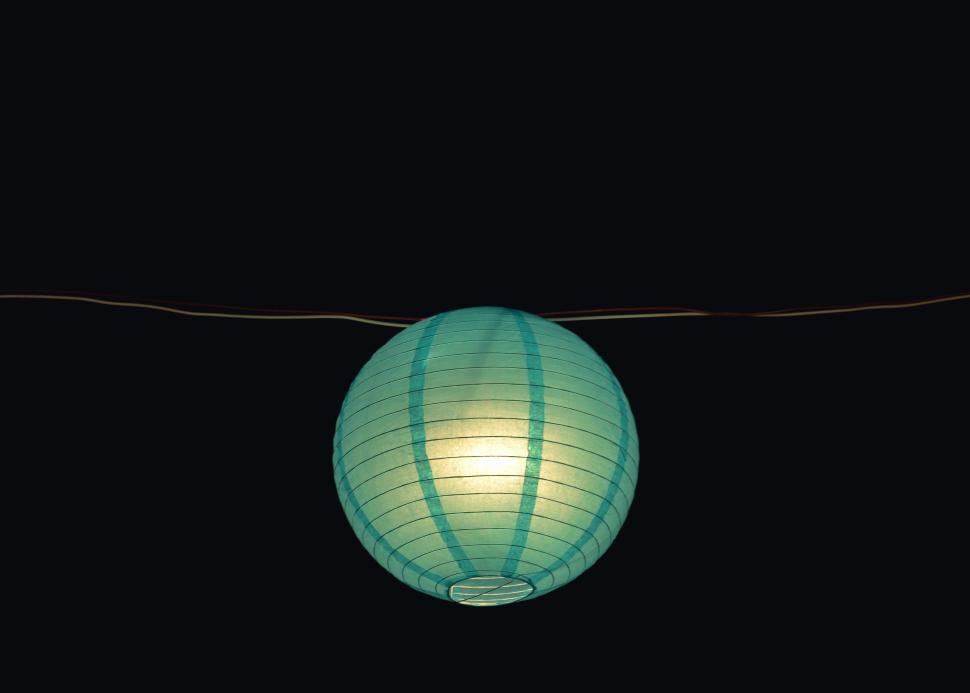 Free Image of Illuminated blue spherical lantern hanging in darkness 