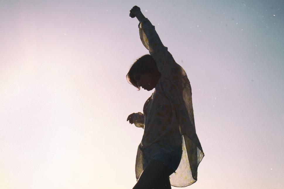 Free Image of Woman silhouetted against sun in carefree joyful pose 