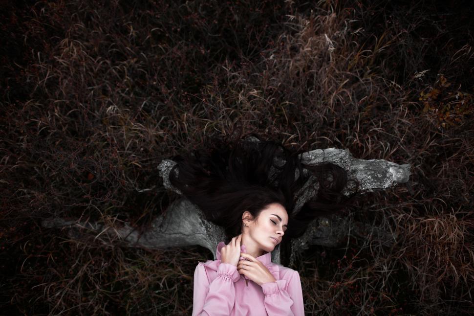 Free Image of Young woman in nature with flowing hair and pink blouse. 