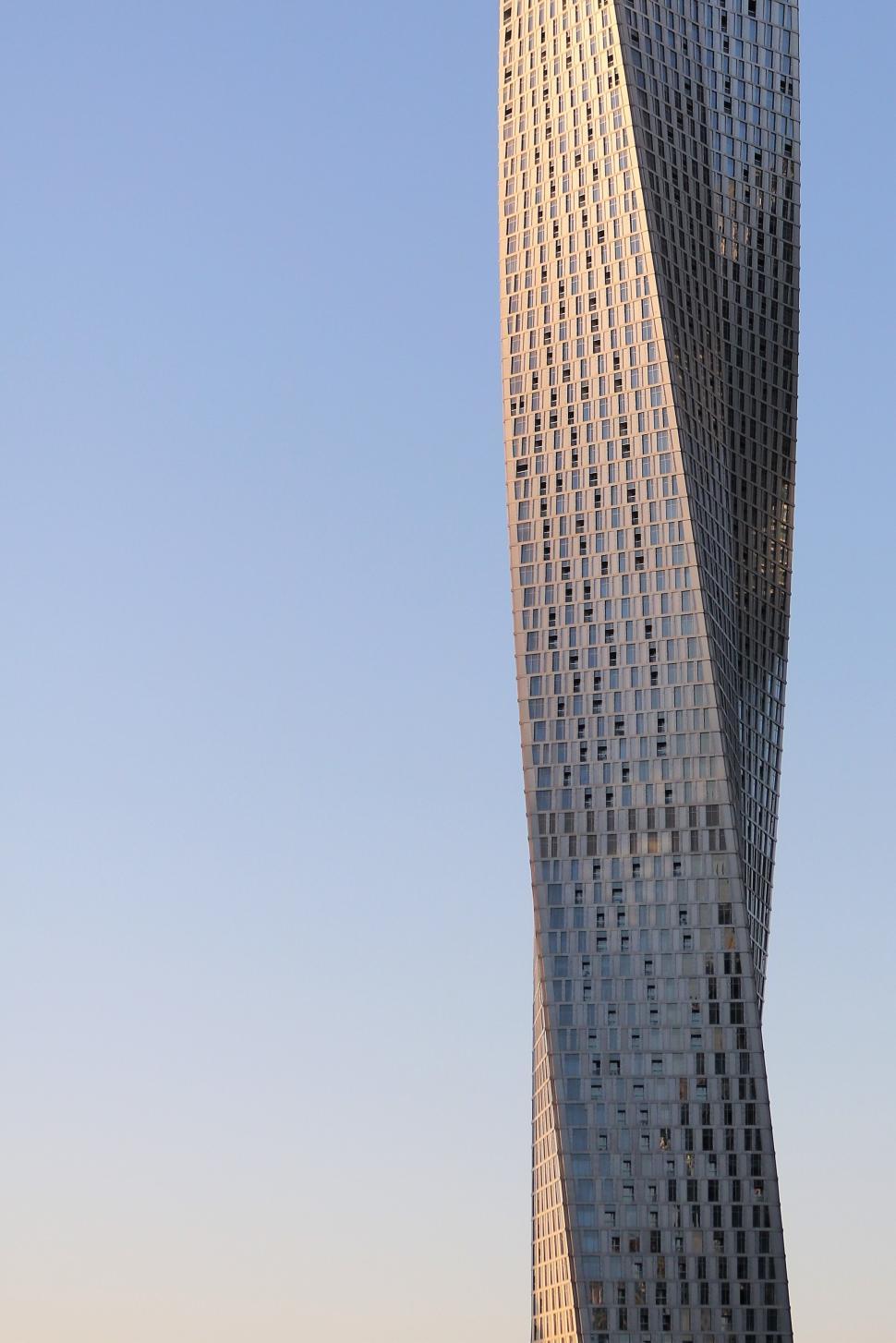 Free Image of Tall twisted skyscraper against a clear blue sky 