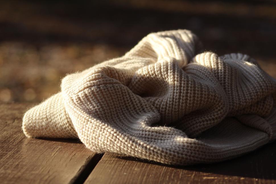 Free Image of Cream knitted fabric on wooden surface in sunlight 