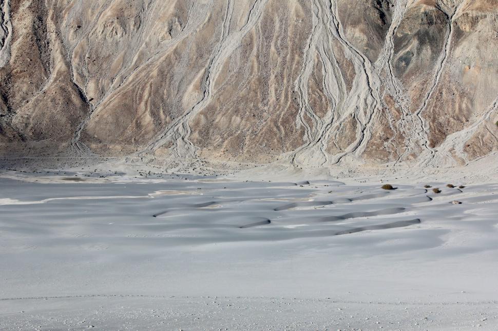 Free Image of Sandy desert landscape with rugged mountain backdrop 