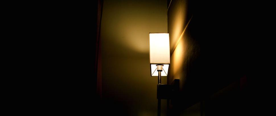 Free Image of Illuminated lamp casting light on a dark room wall 