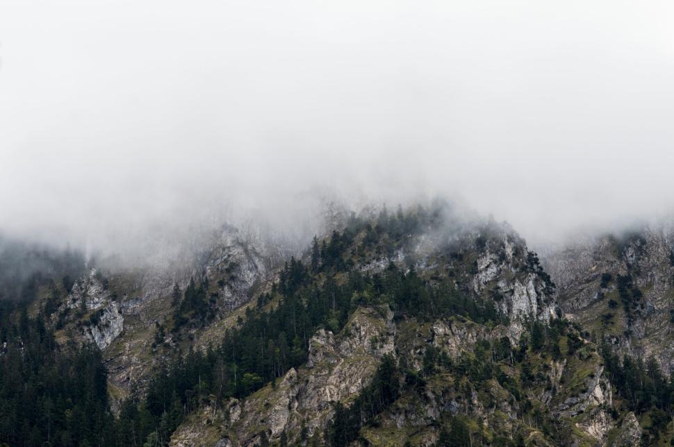 Free Image of Mountain shrouded in mist with forested slopes below 