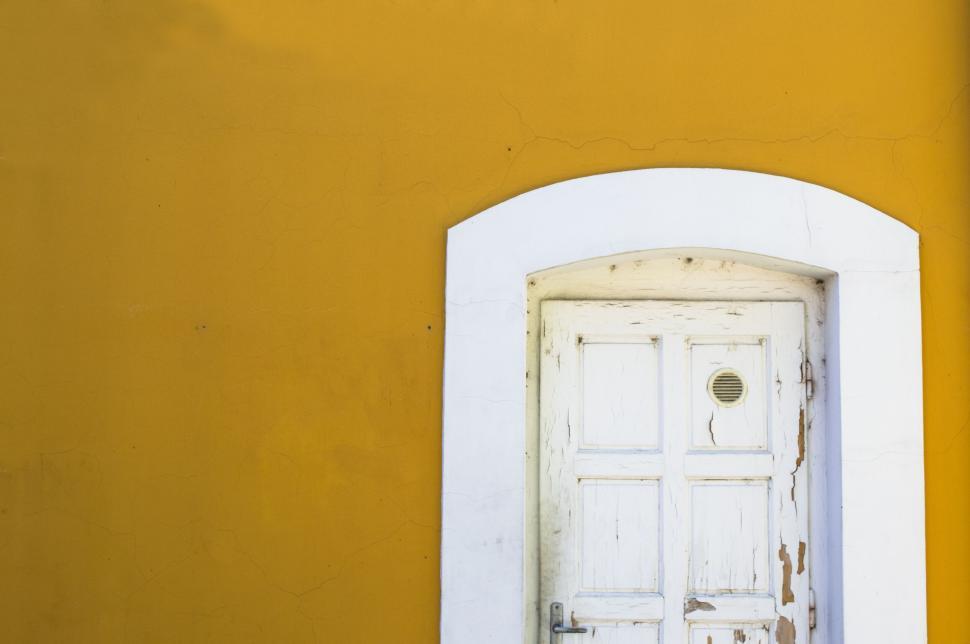 Free Image of White old door against a vibrant yellow background wall. 