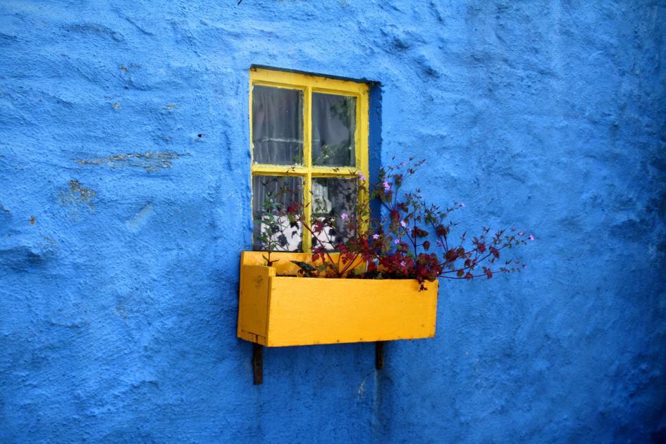 Free Image of Bright yellow window box on vibrant blue wall exterior 