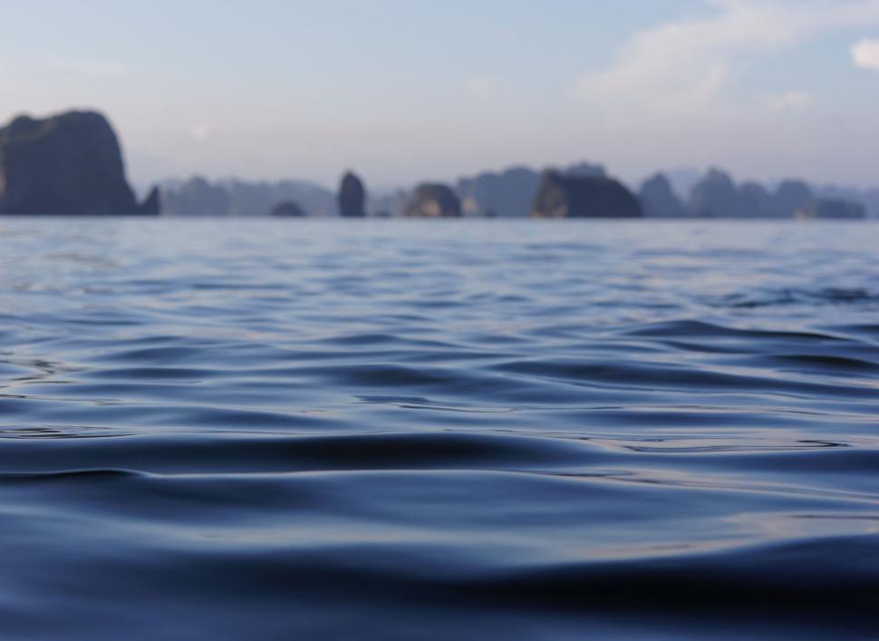 Free Image of Calm sea with distant rock formations under clear sky. 